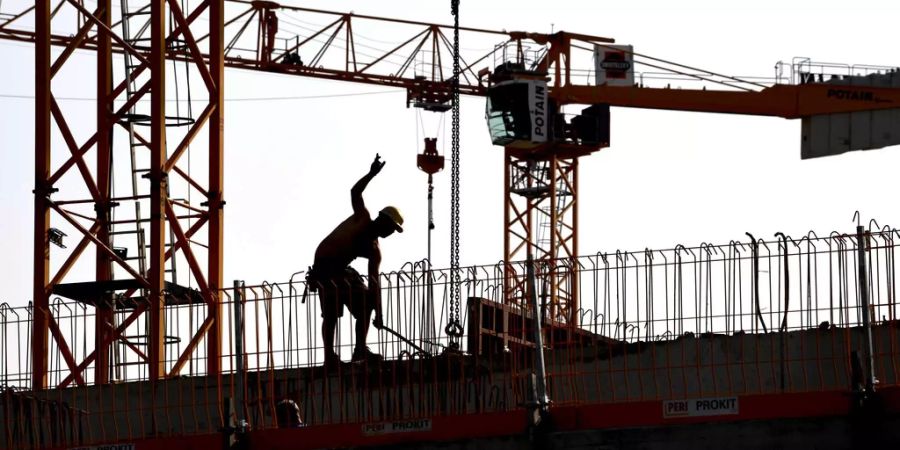 Ein Arbeiter und Kräne auf einer Baustelle.