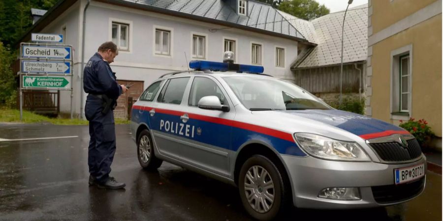 Ein Polizeiauto sperrt die Zufahrt zu einem österreichischen Gebiet auf dem eine Geiselnahme stattfindet.