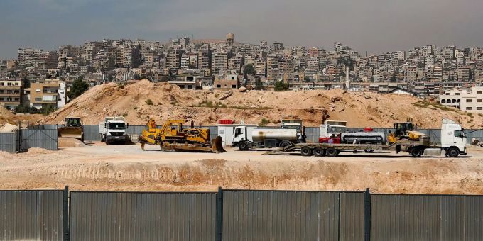 Syrien befindet sich in verwüsteten Gebieten bereits im Wiederaufbau. Einige Lastwagen stehen vor einer Stadt.