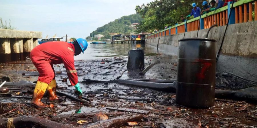 Arbeiter im indonesischen Balikpapan reinigen die ölverseuchte Küste.