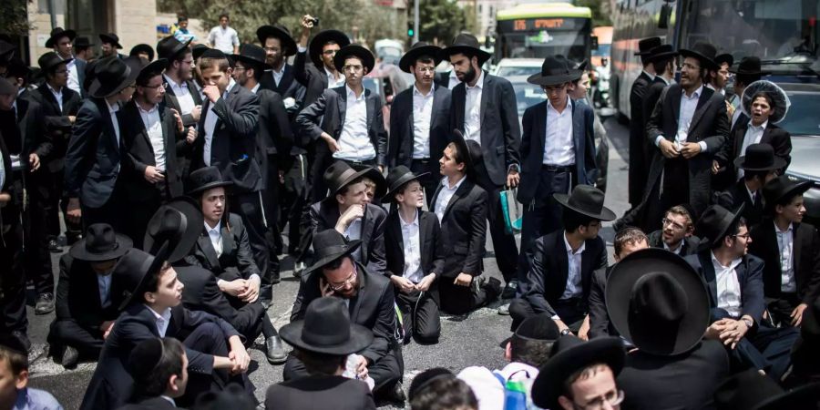 Ultra-orthodoxe jüdische Männer blockieren eine Strasse während einer Demonstration gegen die Rekrutierung von Soldaten.