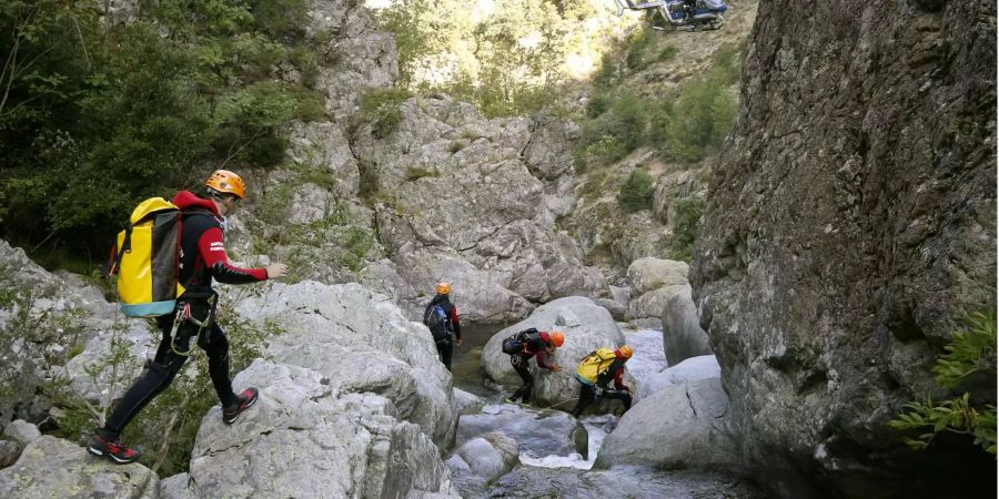 Auf Berg- und Wasserrettung spezialisierte Feuerwehrleute steigen im Canyon Zoicu auf Korsika über Felsen.
