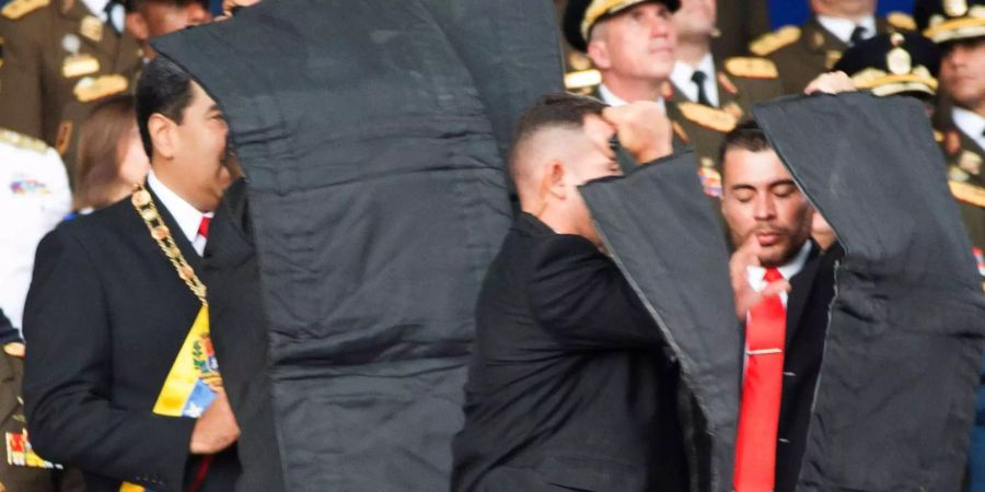 Bodyguards schützen den venezolanischen Präsidenten Nicolas Maduro mit kugelsicheren Schutzmatten.