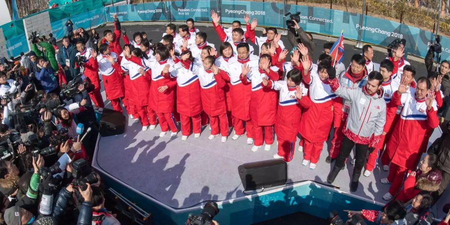 Nordkoreanische Athleten und Funktionäre stehen auf einem Podium im olympischen Dorf während der Willkommenszeremonie für die Sportler aus Nordkorea.