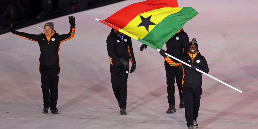 Fahnenträger Akwasi Frimpong (r) läuft bei der Eröffnungsfeier vor dem Team aus Ghana in das Olympiastadion