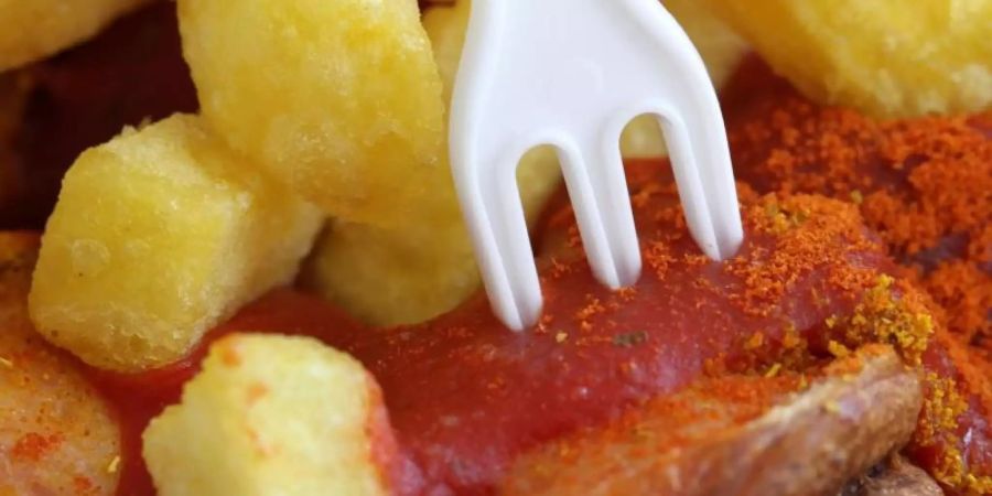 Eine Currywurst mit Pommes frites. Foto: Martin Gerten/Illustration