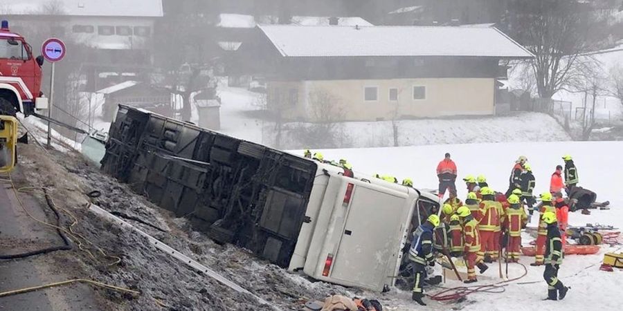 Feuerwehrleute stehen im Februar auf der Bundesstrasse B306 am Ortsausgang von Inzell (Landkreis Traunstein) neben dem umgekippten Reisebus.