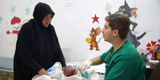 Eine Frau bringt ein Kleinkind in ein Spital in Idlib. Eine Frau bringt ein Kleinkind in ein Krankenhaus in Idlib