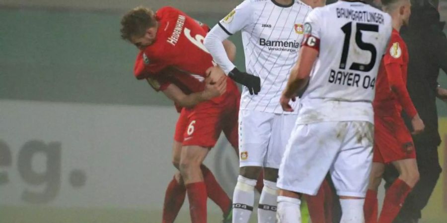 Während die Heidenheimer im Hintergrund ihren Sieg feiern, lassen die Spieler von Bayer Leverkusen nach dem Aus im Pokal-Achtelfinale die Köpfe hängen. Foto: Stefan Puchner