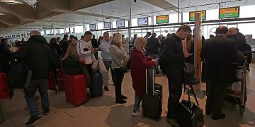 Reisende warten im Flughafen Köln Bonn Airport an einem Schalter.