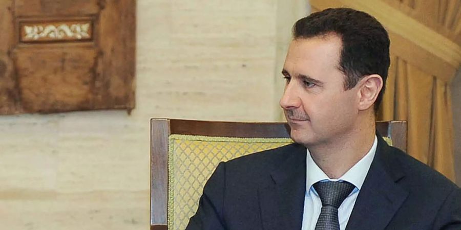 Der syrische Präsident Baschar al-Assad sitzt in einem Stuhl und schaut nach links.