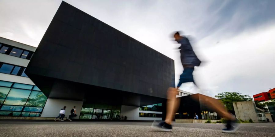 Eine Person geht an der Universität Neuenburg vorbei.