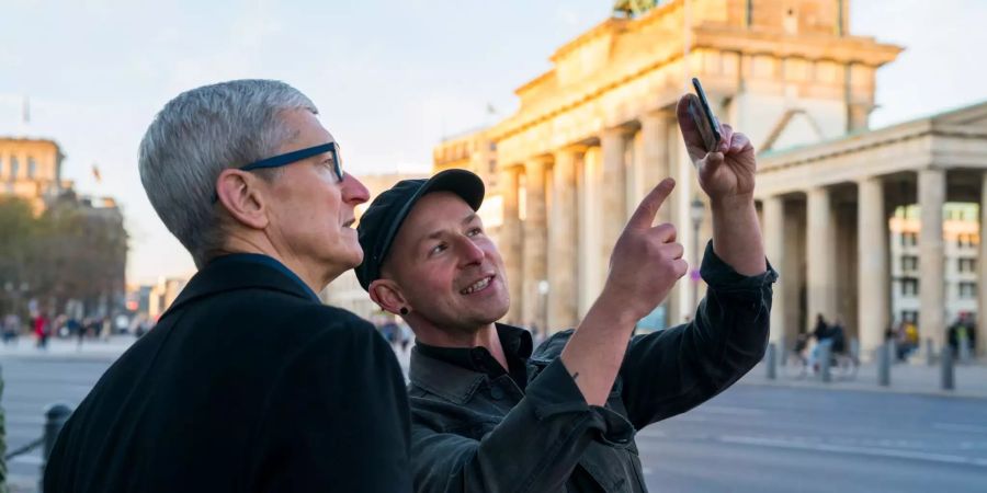 Apple-Chef Tim Cook lässt sich am Brandenburger Tor von Entwickler Peter Kolski das Projekt «MauAR» erklären.