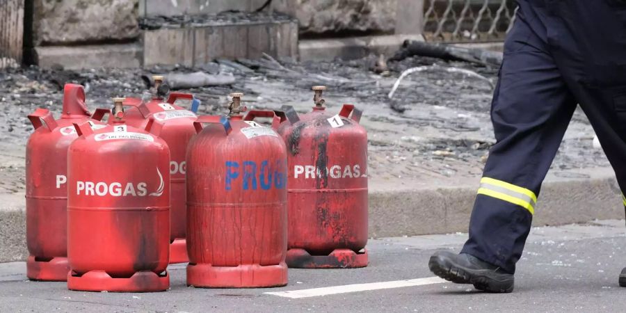 Aus dem Gebäude geholte Gasflaschen stehen vor dem Mehrfamilienhaus, in dem sich eine Explosion ereignete. In dem Döner-Imbiss kam es aus bisher ungeklärter Ursache zu einer Detonation, das Geschäft brannte völlig aus.