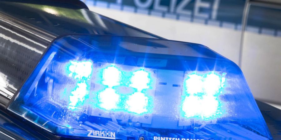 Ein Blaulicht leuchtet während eines Einsatzes auf dem Dach eines Polizeiwagens.