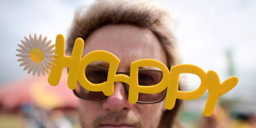 Ein Besucher eines Festivals in Grossbritannien mit einer «Happy»-Brille. Foto: Ben Birchall/PA Wire