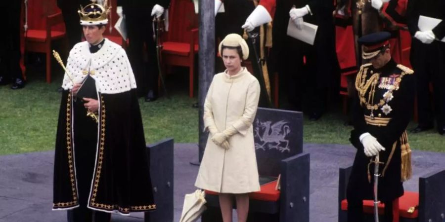 Königin Elizabeth II. (M) und Prinz Charles bei der festlichen Investitur auf Caernarfon Castle. Foto: PA Wire