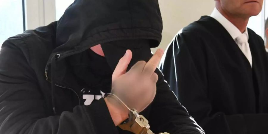Kaltschnäuzig: Der 19-jährige Angeklagte zeigt im Landgericht in Stralsund den Mittelfinger. Foto: Stefan Sauer