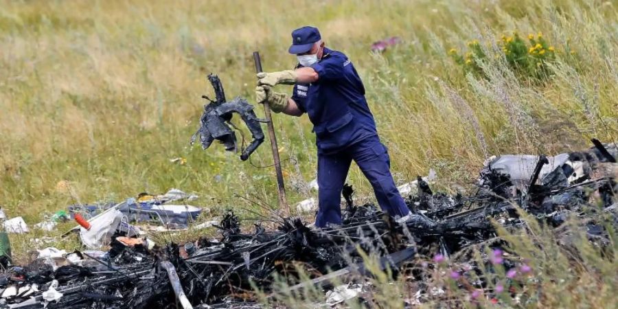 Ein ukrainischer Arbeiter untersucht im Juli 2014 an der Absturzstelle von MH17 Wrackteile der Maschine. Foto: Robert Ghement/epa