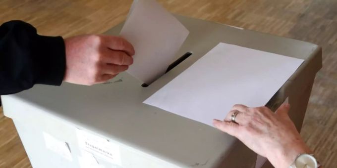Ein Wähler wirft einen Stimmzettel in eine Urne. wahlurne