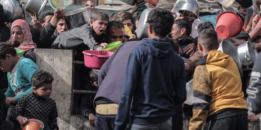 Palästinenser warten an einer Spendenstelle in einem Flüchtlingslager im südlichen Gazastreifen auf Lebensmittel.