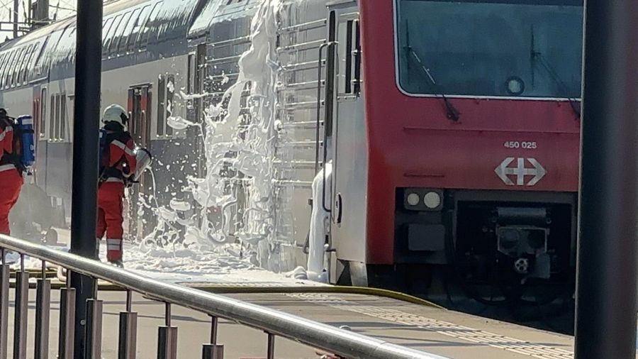 Einsatzkräfte der Feuerwehr löschen den brennenden Zug am Bahnhof Zürich-Altstetten.