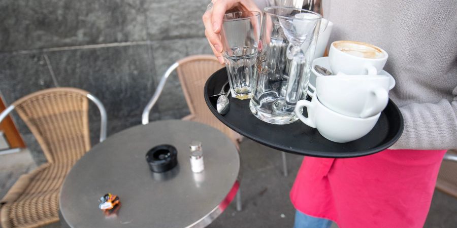 Ein Kellner räumt einen Tisch in einem Restaurant ab.