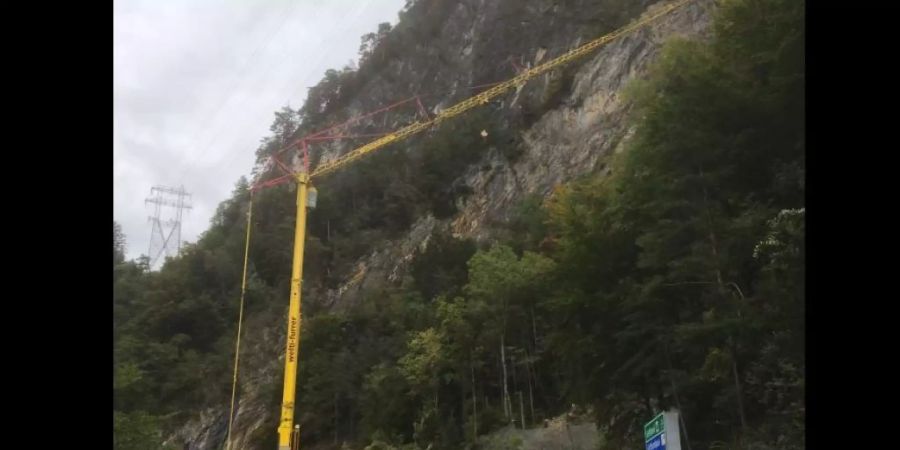 Mit Hilfe eines Pneukrans werden am Axen beschädigte Steinschlagschutznetze repariert.