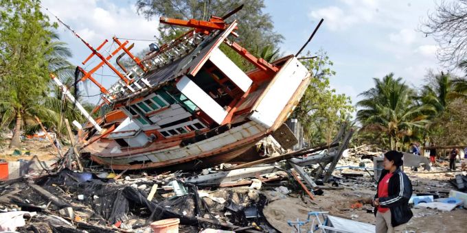 ARCHIV - 05.01.2005, Thailand, Khao Lak: Nataya Pumsi steht zwischen Trümmern vor einem Boot. Am zweiten Weihnachtstag 2004 verwüsteten gewaltige Flutwellen Küsten am Indischen Ozean. Foto: Ricahrd Vogel/AP/dpa +++ dpa-Bildfunk +++ Tsunami 2004