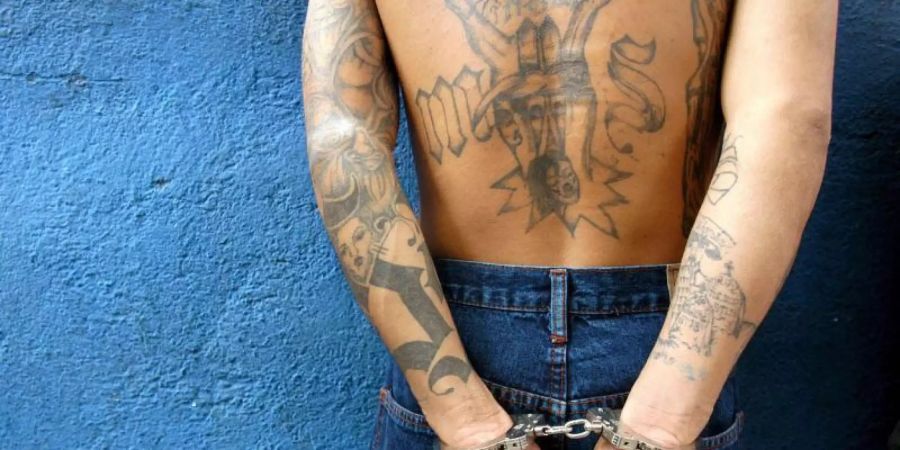 Auf dem Archivbild steht ein Mitglied der Verbrecherbande «Mara Salvatrucha» (M-13) nach seiner Festnahme mit Handschellen an einer Wand. Foto: epa efe Roberto Escobar/epa efe/dpa