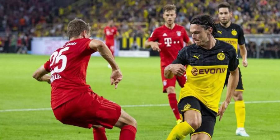 Treffen im Bundesliga-Topspiel aufeinander: Dortmunds Nico Schulz (r) und Bayerns Thomas Müller. Foto: Guido Kirchner/dpa