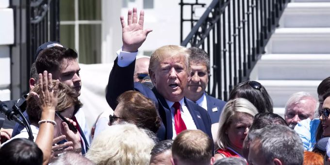 US-Präsident Donald Trump steht inmitten einer Menschengruppe. US-Präsident Donald Trump