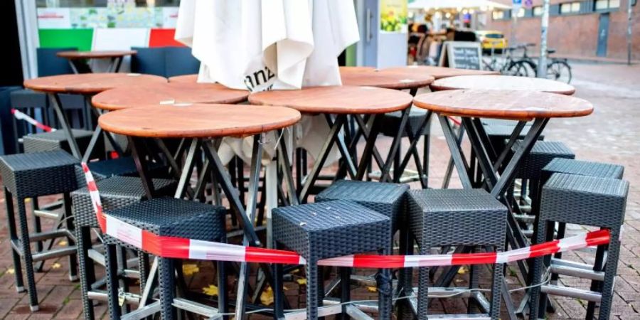 Mit Flatterband abgesperrte Tische und Stühle stehen vor einer Pizzeria in Hannover. Foto: Hauke-Christian Dittrich/dpa