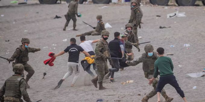 Spanische Soldaten versuchen, Migranten am Strand in der spanischen Enklave Ceuta festzunehmen. Migranten in Spanien