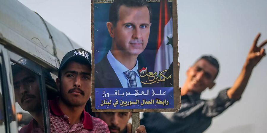 Ein Syrer hält ein Bild des syrischen Präsidenten al-Assad. Er und weitere Wähler machen sich auf den Weg, um ihre Stimmen abzugeben. Vor der syrischen Präsidentschaftswahl am 26. Mai hat in den Botschaften im Ausland die Stimmabgabe begonnen. Foto: Marwan Naamani/dpa Foto: Marwan Naamani/dpa