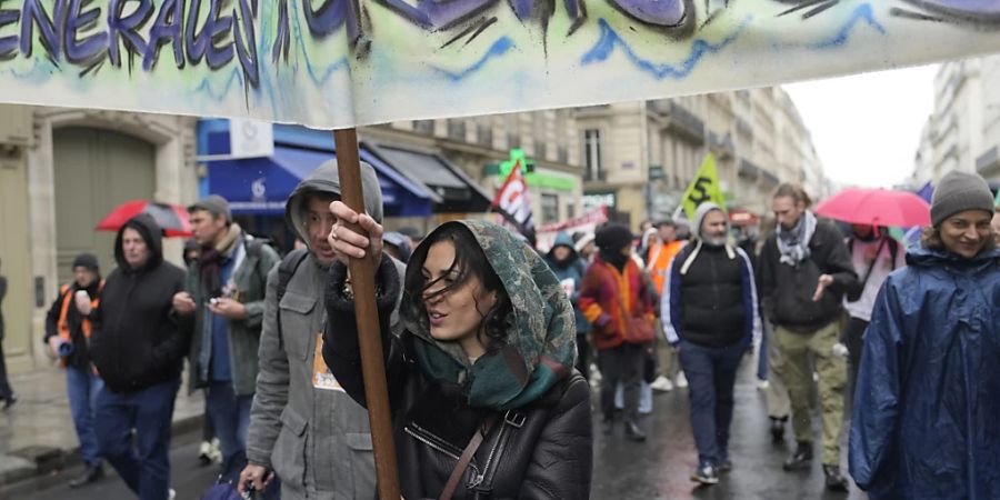 Menschen ziehen im Rahmen eines Protests durch die Strassen. In Frankreich haben vor der Entscheidung des Verfassungsrats zur Rentenreform von Präsident Macron erneut Menschen protestiert. Foto: Lewis Joly/AP/dpa