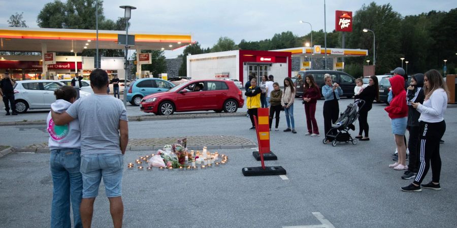 Menschen stehen neben Blumen und Kerzen auf einen Parkplatz, wo die zwölfjährige Adriana  aus einem vorbeifahrenden Auto heraus erschossen wurde (2020).