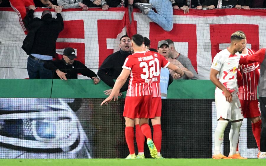 Freiburg-Spieler versuchen die eigenen Fans zu beruhigen.