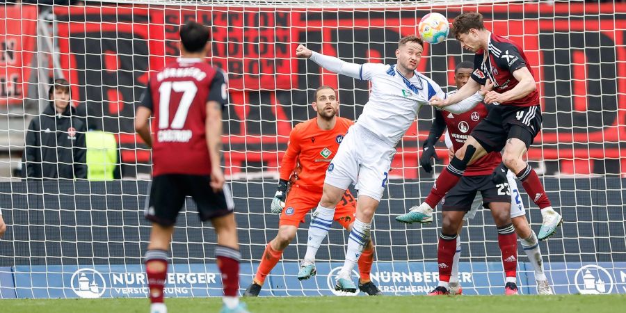 Nürnberger James Lawrence (r) liefert sich mit Karlsruhes Christoph Kobald (M) ein Kopfballduell.