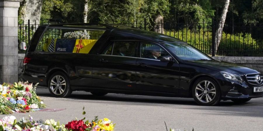 Der Leichenwagen mit dem Sarg von Königin Elizabeth II., der mit der königlichen Standarte von Schottland behängt ist, verlässt Schloss Balmoral und beginnt seine Fahrt nach Edinburgh. Foto: Owen Humphreys/PA Wire/dpa