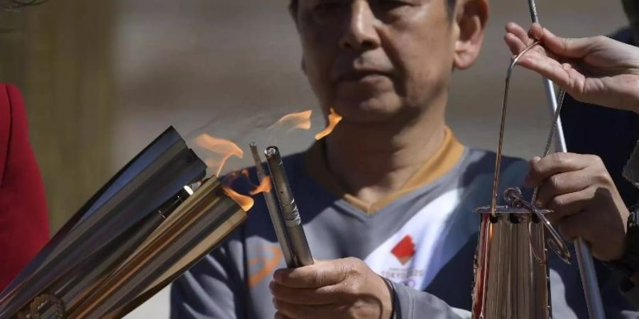 Die olympische Fackel wird während der Übergabe des olympischen Feuers an die Organisatoren der Sommerspiele von Tokio entzündet. Foto: Aris Messinis/AFP POOL/AP/dpa