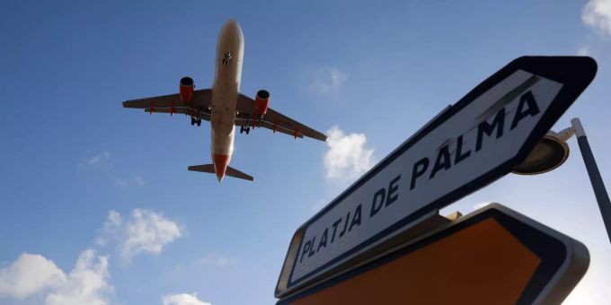 Ein Flugzeug überfliegt bei der Landung auf Mallorca ein Schild, das die Richtung nach Playa de Palma anzeigt. Mallorca