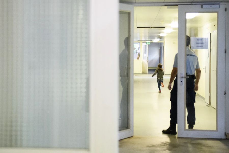 Ein Securitas Mitarbeiter beobachtet ein Kind in einem Gang im Bundesasylzentrum Perreux fotografiert anlässlich einer Medienbesichtigung am Mittwoch, 11. Mai 2016, in Perreux.