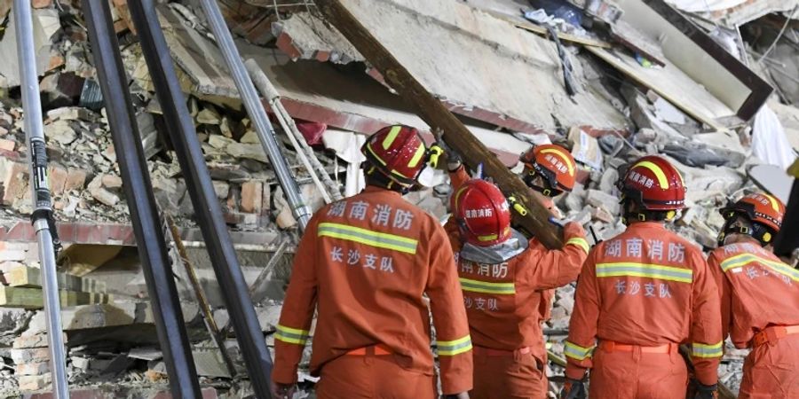Einsatzkräfte vor Trümmern des eingestürzten Gebäudes