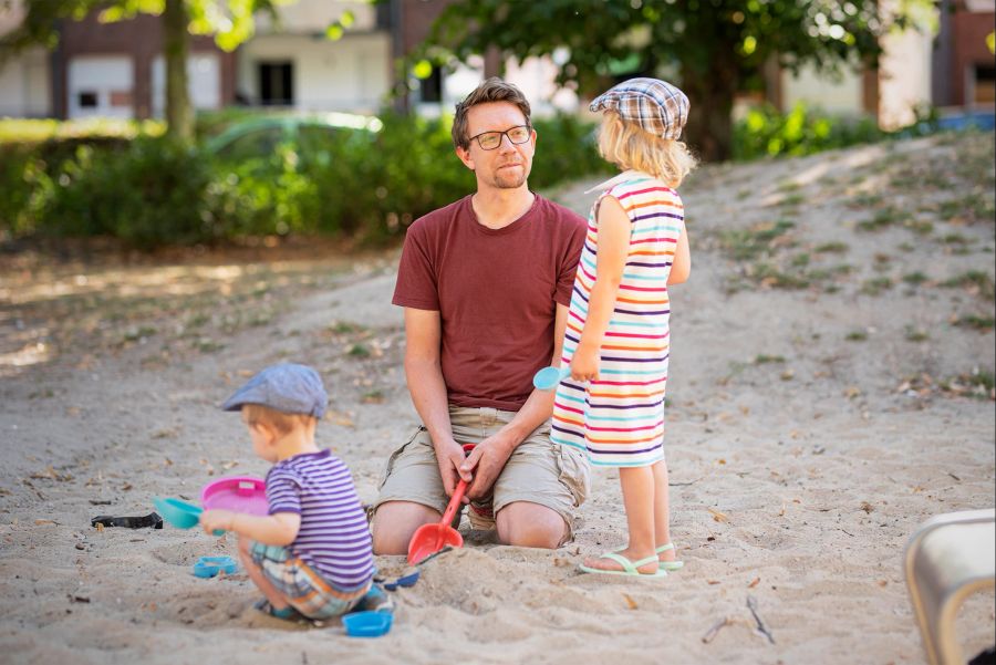 Mann Sandkiste Junge Mädchen Schaufel spielen