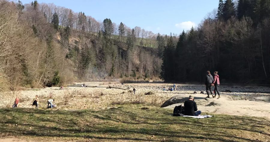 Gruppen von Menschen an einem Bachlauf.