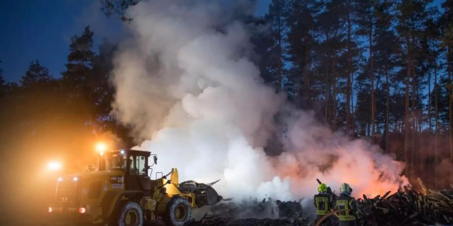 Die Feuerwehr löscht etwa 10.000 Kubikmeter brennende Holzstämme im Landkreis Barnim. Foto: Jörg Carstensen/dpa