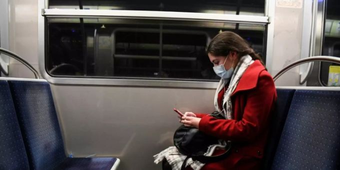Eine Smartphonenutzerin mit Mundschutz Coronavirus
