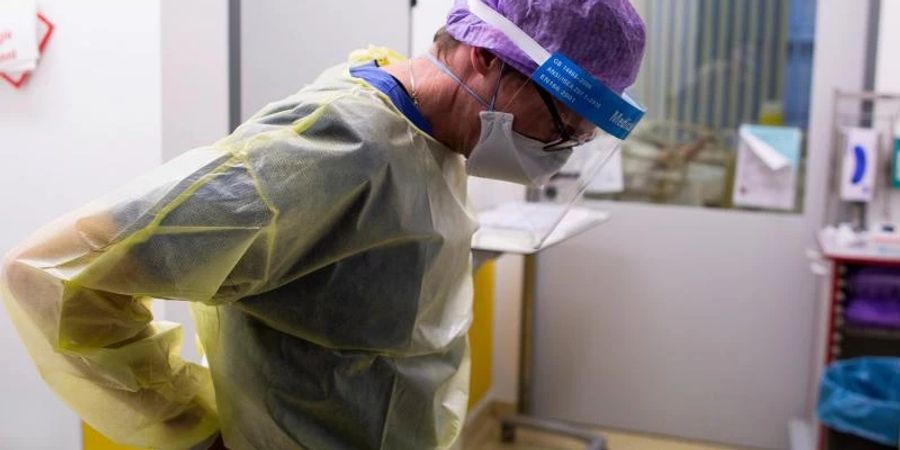 Ein Arzt des Krankenhauses Düren zieht seine Schutzkleidung an, um auf der Intensivstation des Krankenhauses Düren einen Covidpatienten zu untersuchen. (Archivbild). Foto: Thomas Banneyer/dpa