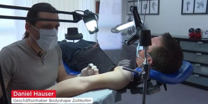 Daniel Hauser tätowiert neu mit einer Plexiglaswand vor dem Kunden. Daniel Hauser tätowiert neu mit Plexiglaswand vor dem Kunden.